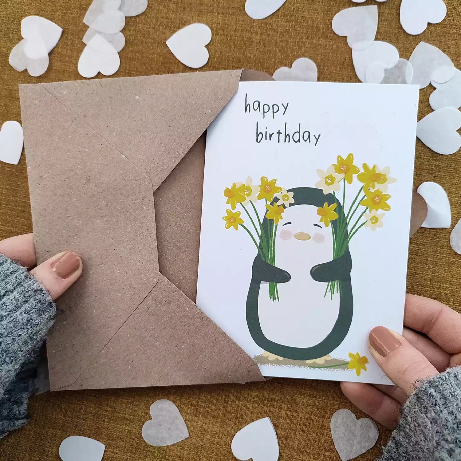 birthday card featuring a penguin holding daffodils