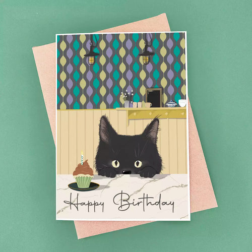 black cat birthday card peeking over kitchen worktop and patterned wallpaper background