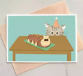 birthday card featuring a cat looking up at a caterpillar cake.
