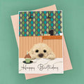 cockerpoo birthday card peeking over kitchen worktop and patterned wallpaper background