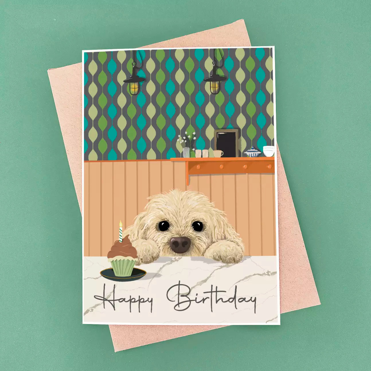 cockerpoo birthday card peeking over kitchen worktop and patterned wallpaper background
