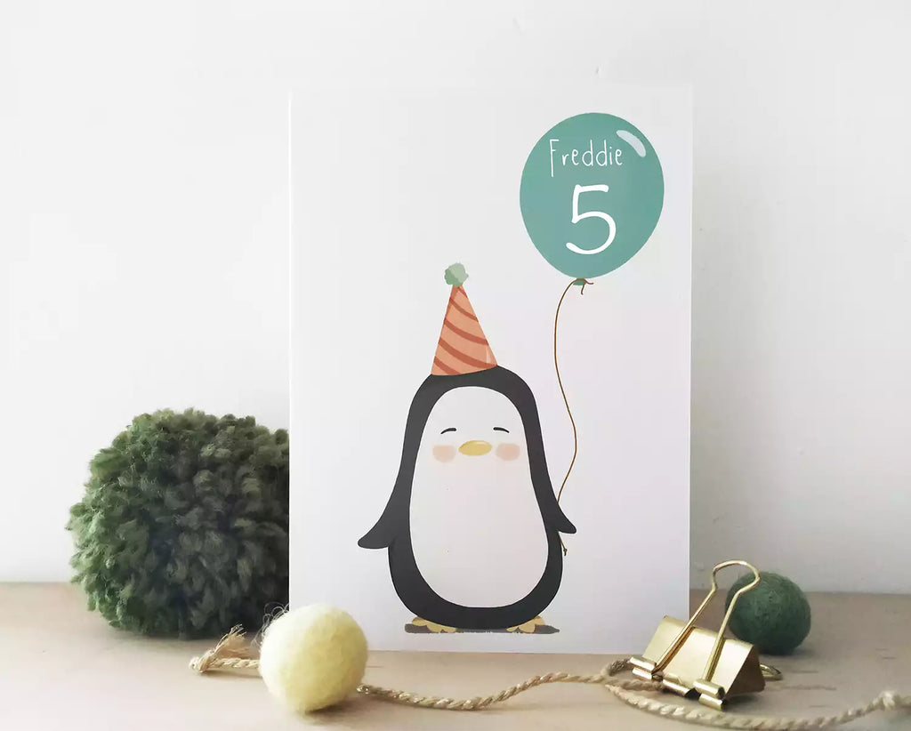 birthday card with a penguin holding a balloon. personalised with name and age