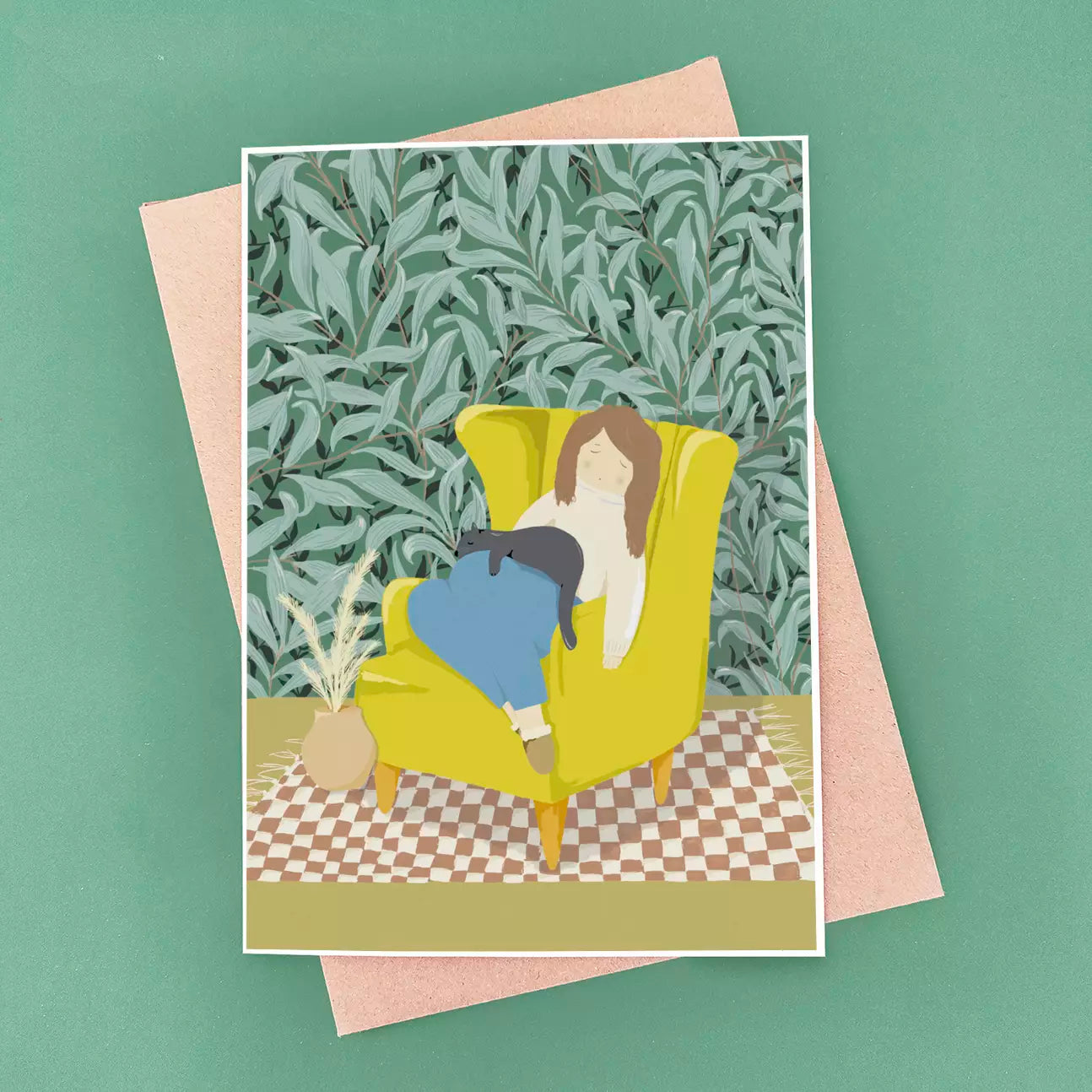 Black cat sleeping on their cat mum in yellow armchair, with patterned wallpaper background