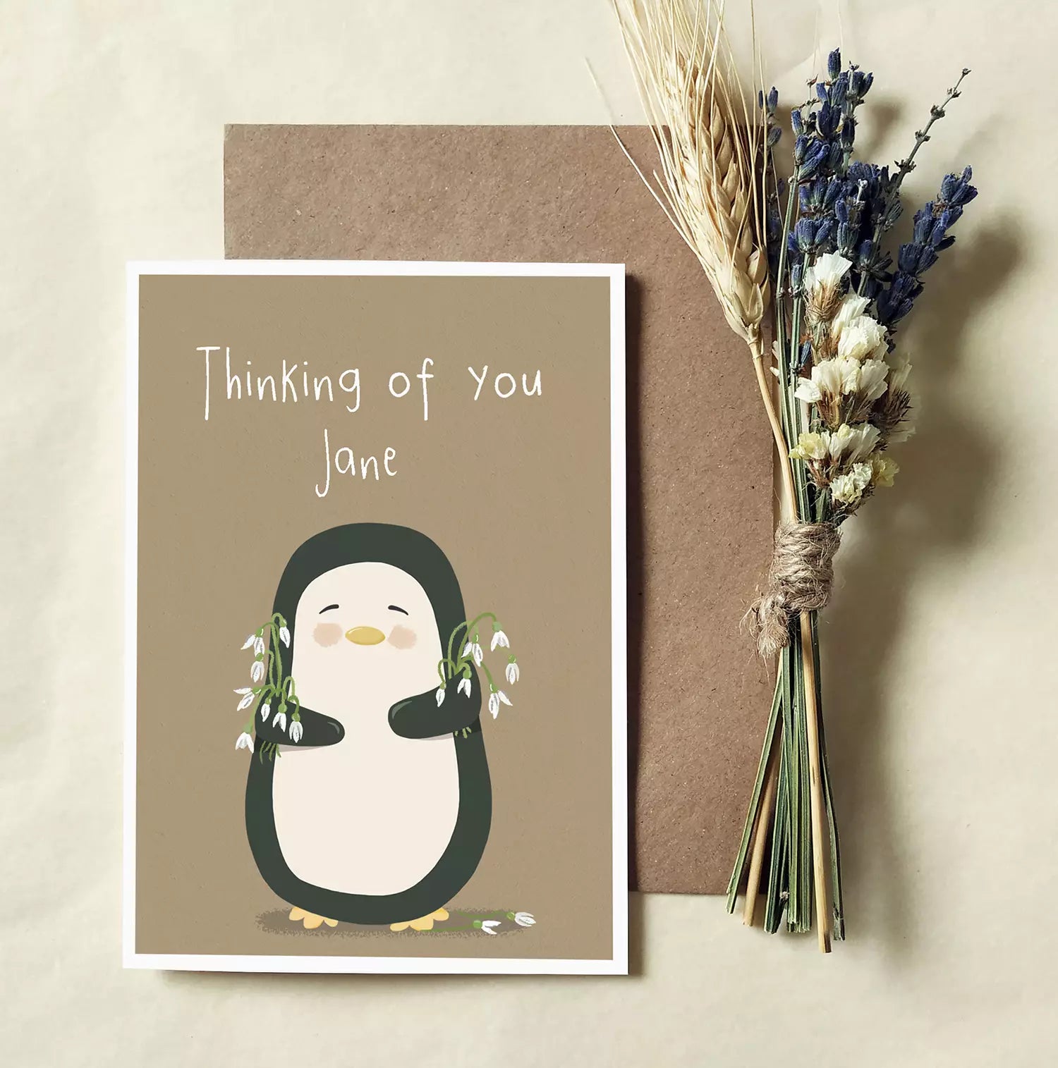 sympathy card with penguin holding snowdrops. text reads 'thinking of you'