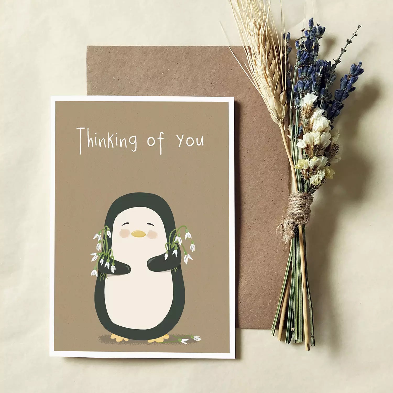 sympathy card with penguin holding snowdrops. text reads 'thinking of you'